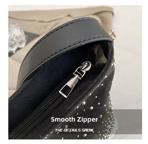 Detail shot of smooth silver metal zipper and rhinestone embellishments on a black bag