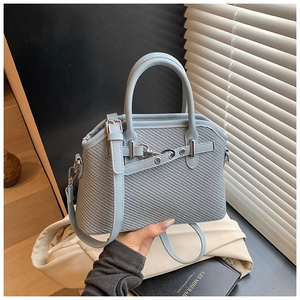 Détail d'un sac à main bleu clair texturé avec motif tissé et boucle en métal