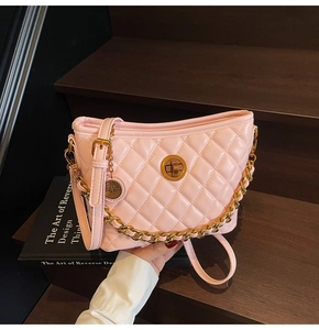 Detail of pink quilted bucket bag with golden chain strap and round metal swivel lock