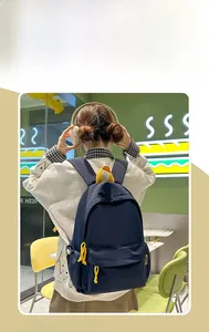 Detail view of a navy blue school backpack with yellow zippers worn by a student