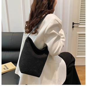 Fashionable black rhinestone bucket bag styled on a white blazer outfit in a chic interior