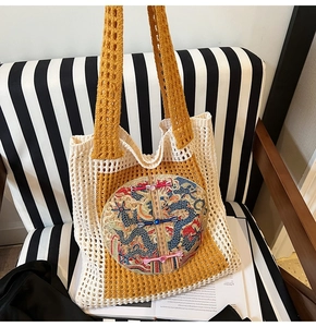 Detail view of yellow woven tote bag featuring dragon embroidery and mesh crochet texture