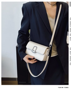 Close-up of minimalist off-white lychee texture leather shoulder bag with silver metal buckle