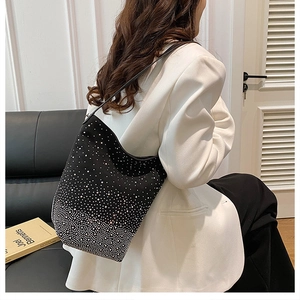Detailed close-up of a black gradient rhinestone shoulder bag on a white suit jacket
