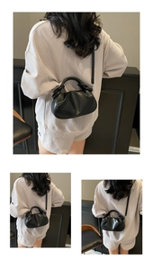 Detail of a black pleated cloud bag with versatile top handle and slim crossbody strap