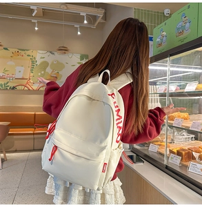 Detail of canvas backpack with large red FUMIAO letter embroidery and rope zippers