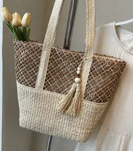 Détail d'un sac cabas bicolore en paille avec tissage ajouré et pompon en perles de bois