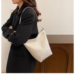 Detailed macro view of the sparkling rhinestone texture on this cream white bucket bag