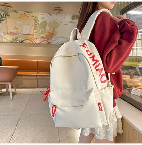 Detail view of white canvas backpack featuring red FUMIAO letter print and drawstring zip