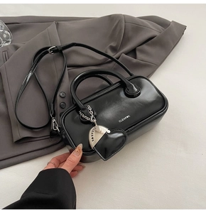 Detail of black rectangular leather handbag with heart charm and silver strap hardware