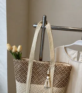 Vue détaillée du sac cabas en paille tressée avec bandoulière large et pompon en bois