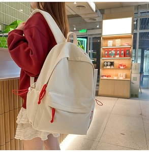 Close-up of minimalist cream high-density nylon backpack with vibrant red zipper pull cords
