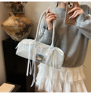 Detail der hellblauen Boston-Tasche aus Wildleder mit weißen Spitzenschleifen und Schloss