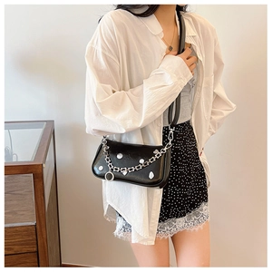 Detail of a chic black glossy leather handbag featuring silver chains and heart charms