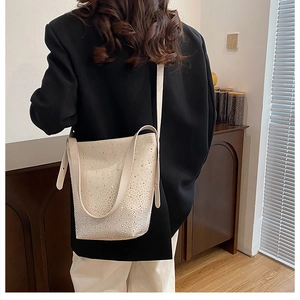 Detail view of cream white bucket bag featuring elegant silver gradient rhinestone embellishment