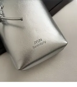 Detail of silver metallic textured crossbody bag with JYUN Serendipity logo print