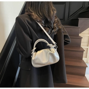 Detail showing metallic silver pleated handbag with embossed logo and sleek handle