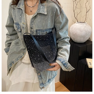 Close-up of black shoulder bag with silver rhinestones on a stylish model with white dress