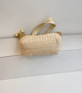 Détail du tissage en chevrons et des lanières marron sur un grand sac cabas en paille beige