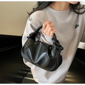 Close-up of black ruched cloud bag featuring a unique circular chain-link top handle