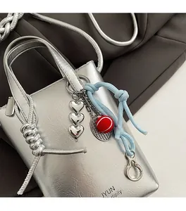 Detail of silver metallic mini bag with heart charms and tennis racket accessory