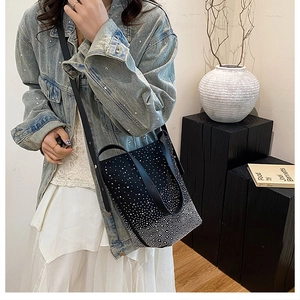 Detail of black gradient rhinestone bucket bag worn by model in casual chic outfit