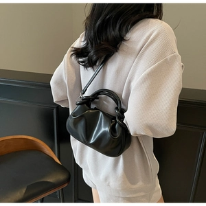 Detail shot of a black pleated cloud bag featuring a thick knotted handle and shoulder strap