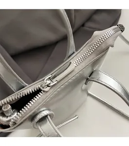 Close-up of the smooth metal zipper closure on the silver metallic handbag with gray lining