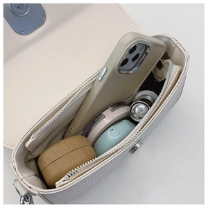 Macro shot showing internal capacity of the off-white leather bag with daily essentials