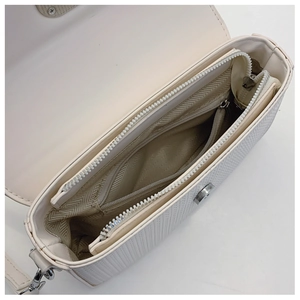 Detailed interior of a textured beige crossbody bag with pockets and magnetic closure
