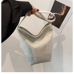 Detail of beige bucket bag with shimmering silver rhinestones and leather handle strap