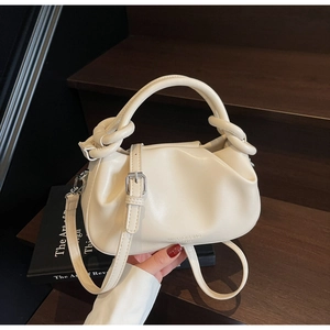 Macro view of cream pleated cloud bag featuring knotted handles and fine leather texture