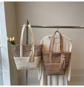 Détail de sacs cabas en paille tissés main avec motif résille et pompons en perles de bois