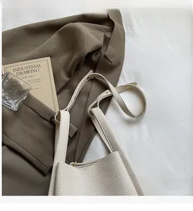 Detail view of lychee-textured leather handbag with golden rivet accents and sturdy handle