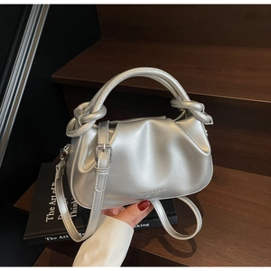 Close-up of silver pleated handbag with knotted handle detail on wooden stairs