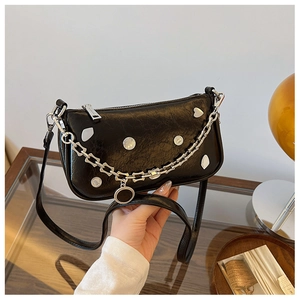 Detail of black glossy underarm bag with silver heart sequins and chunky metal chain strap
