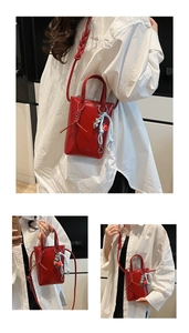 Detail of red patent leather mini bag with woven knot and decorative heart charms