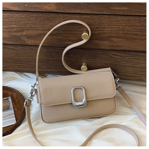 Close-up of beige woven texture and rectangular silver metal buckle on crossbody bag