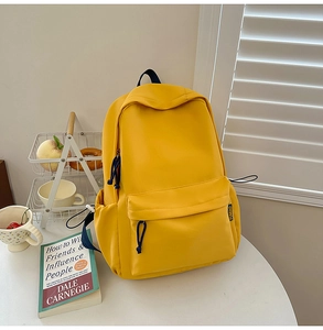 Detailed close-up of yellow casual backpack with side label and woven zipper pulls