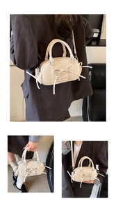 Detail of cream-white Boston bag featuring ballet-style ribbon lacing and bow design