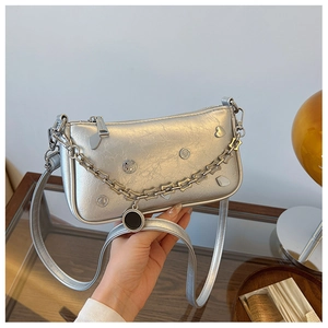 Detail of silver metallic underarm bag featuring chain strap and heart charms