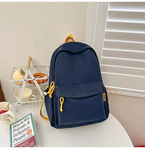 Detail of navy blue backpack with yellow accents, front pocket, and canvas texture