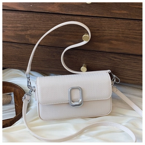 Close-up of cream woven texture and large silver buckle on minimalist crossbody bag