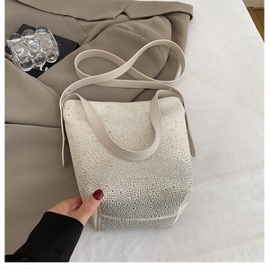 Detailed macro view of the cream bucket bag with sparkling silver rhinestone finish
