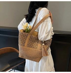 Détail du sac cabas en paille tissé à la main avec motif ajouré et pompon décoratif