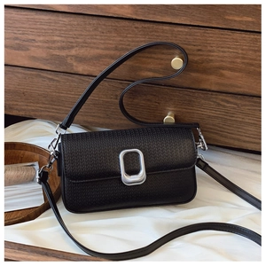 Detail of black woven texture handbag featuring a matte silver oval buckle and straps