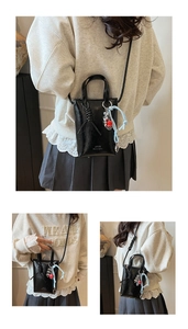 Detail of black glossy bucket bag featuring Jyun Serendipity text and colorful charms