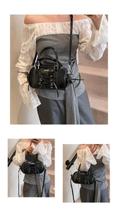 Detail of black patent leather Boston bag featuring silver eyelets and ballet lace-up bow