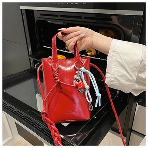 Glossy red patent leather mini crossbody bag with knots and heart charm detail