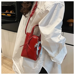 Detail of red patent leather mini tote bag with woven strap and heart charm